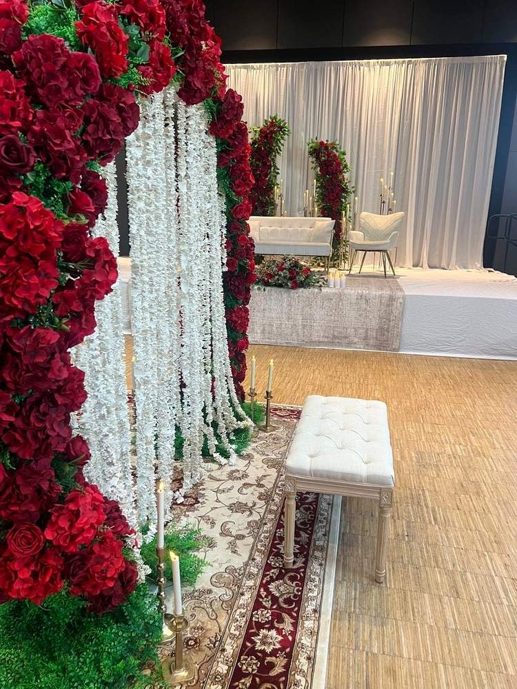 Red floral wedding ceremony setup with divider, stage and table styling